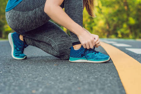 Female runner tying her shoes preparing for jogging outside .Young girld runner getting ready for training. Sport lifestyleの写真素材