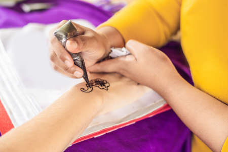 Woman is drawing on hand. Draw on the hand Indian mehendi picture.の写真素材