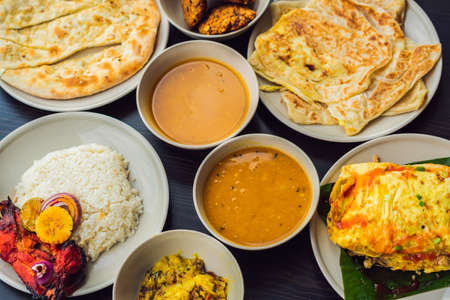 Assorted indian food on dark wooden background. Dishes and appetizers of indian cuisine. Curry, butter chicken, rice, lentils, paneer, samosa, naan, chutney, spices. Bowls and plates with indian food.の写真素材