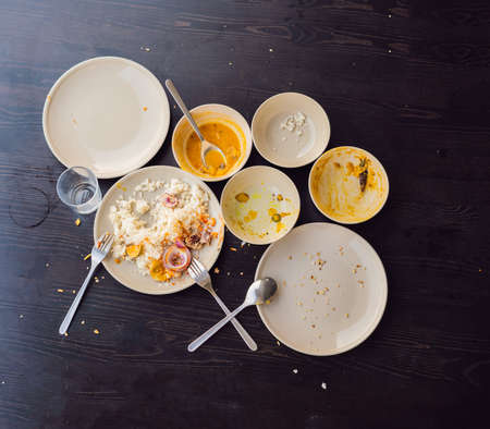 The remains of food in plates, crumbs on the table after lunch or dinner.の写真素材