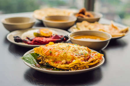 Assorted indian food on dark wooden background. Dishes and appetizers of indian cuisine. Curry, butter chicken, rice, lentils, paneer, samosa, naan, chutney, spices. Bowls and plates with indian food.の写真素材
