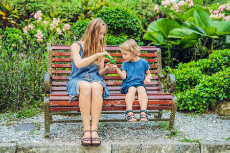 Mother and son using wash hand sanitizer gel in the park before a snack.の写真素材