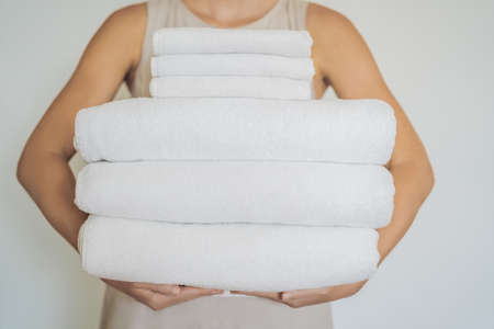 A woman is holding a stack of white towels. Concept of service in hotels, laundry, spa.の写真素材