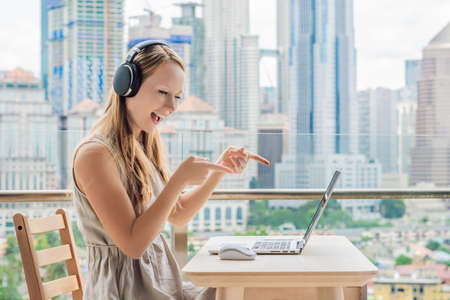 Young woman teaches a foreign language or learns a foreign language on the Internet on her balcony...