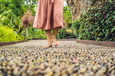 Woman Walking On A Textured Cobble Pavement, Reflexology. Pebble stones on the pavement for foot...