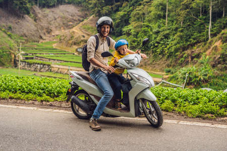 Father and son are traveling on a moped on a tea plantation in Malaysia. Traveling with children concept.の写真素材