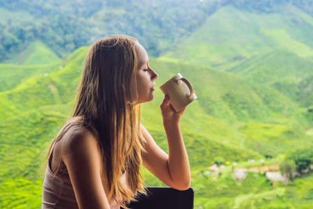 Young woman Drinking Healthy Green Tea against a tea plantation. Healthcare or Herbal medicine concept.の写真素材