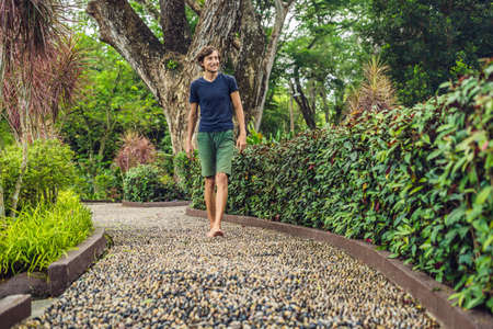 Man Walking On A Textured Cobble Pavement, Reflexology. Pebble stones on the pavement for foot...