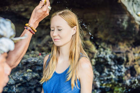 Woman is a tourist in Bali. The ritual of ablution with holy water and on her forehead prikleeli...