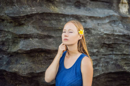 Woman is a tourist in Bali. The ritual of ablution with holy water and on her forehead prikleeli rice and put the flower ear.の写真素材