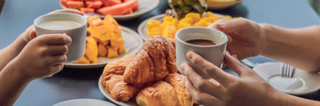 Happy family having breakfast on the balcony. Breakfast table with coffee fruit and bread croisant...