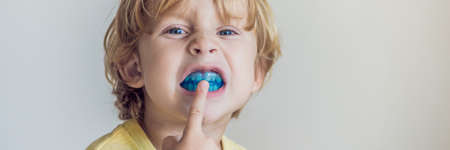 Three-year old boy shows myofunctional trainer to illuminate mouth breathing habit. Helps equalize the growing teeth and correct bite. Corrects the position of the tongue. BANNER, long formatの写真素材