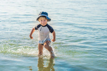 happy little boy running on sand tropical beach.の写真素材