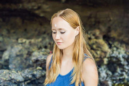 Woman is a tourist in Bali. The ritual of ablution with holy water and on her forehead prikleeli rice and put the flower ear.の写真素材
