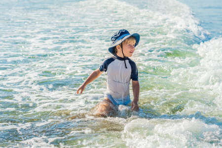happy little boy running on sand tropical beach.