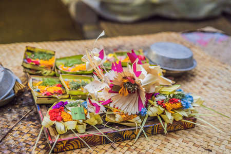 Traditional balinese offerings to gods in Bali with flowers and aromatic sticks.