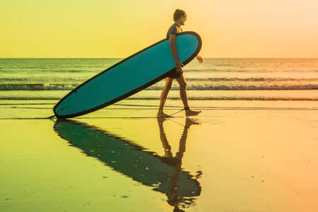 Vacation Silhouette Of A Surfer Carrying His Surf Board Home At Sunset With Copy Space.の写真素材