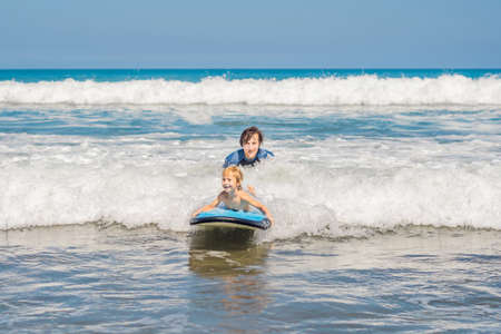 Father teaching his young son how to surf in the sea on vacation or holiday. Travel and sports with children concept.の写真素材