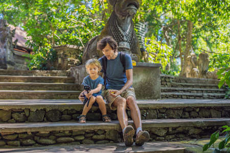 Dad and son travelers discovering Ubud forest in Monkey forest, Bali Indonesia. Traveling with children concept. Videoblog, Selfie..の写真素材