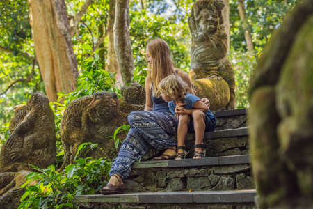 Mom and son travelers discovering Ubud forest in Monkey forest, Bali Indonesia. Traveling with...