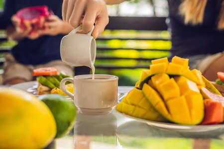 The moment pouring milk into coffee. Woman pouring cream in coffee.の写真素材