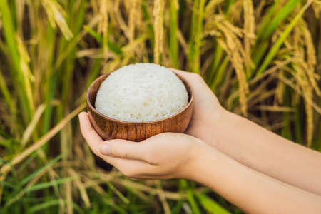 The hand holds a cup of boiled rice in a wooden cupの写真素材