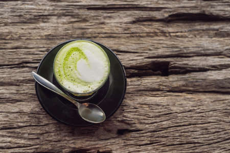 Cup of matcha latte against the old wooden table.の写真素材