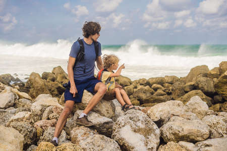 Dad and son travelers on amazing Melasti Beach with turquoise water, Bali Island Indonesia....