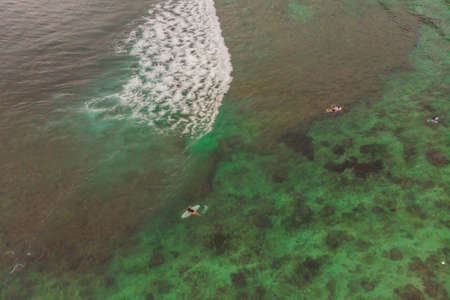 Surfers on the waves in the ocean, top view.