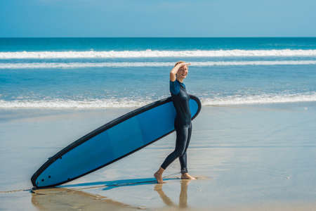 Young woman in swimsuit with surf for beginners ready to surf. Positive emotions.