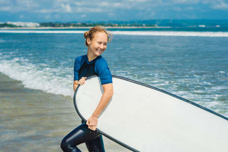 Young woman in swimsuit with surf for beginners ready to surf. Positive emotions.