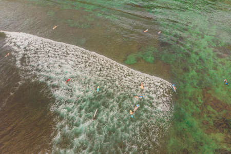 Surfers on the waves in the ocean, top view.