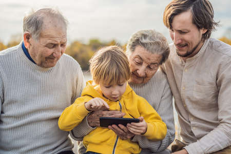 The boy shows the photo on the phone to his grandparents.の写真素材