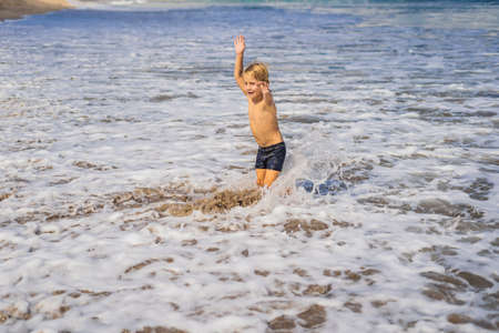 Boy playing on the beach in the water.の写真素材