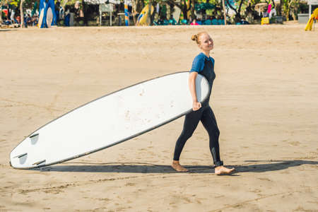Young woman in swimsuit with surf for beginners ready to surf. Positive emotions.の写真素材