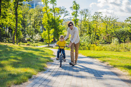 Father teaches his son ride a bicycle.の写真素材