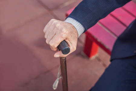 Old man hand holding walking stick outdoor.の写真素材