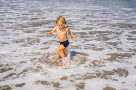 Boy playing on the beach in the water.の写真素材