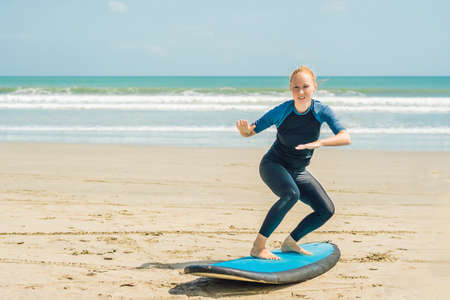 Young woman is training to stand on the surf before the first surfing lesson.の写真素材