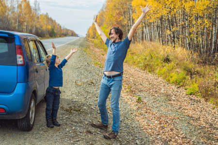 Dad and son are resting on the side of the road on a road trip. Road trip with children concept.の写真素材