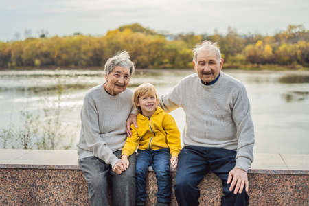 Senior couple with baby grandson in the autumn park.の写真素材