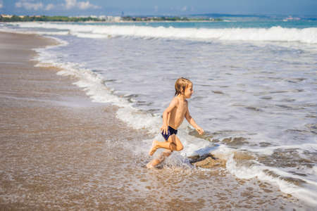 Boy playing on the beach in the water.の写真素材