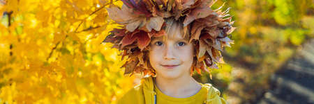 Portrait of little smiling child with wreath of leaves on head of sunny autumn park.の写真素材