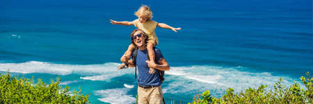 Dad and son travelers on a cliff above the beach.の写真素材