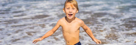 Boy playing on the beach in the water.の写真素材