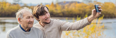 A man takes a selfie with an older man.の写真素材