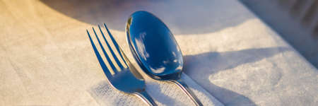 Fork and spoon with reflection of clouds. Dinner in the open air concept.
