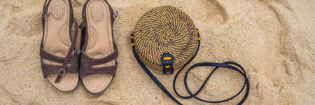 Sandals and Balinese wicker bag on the sand.の写真素材