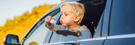 Boy blowing bubbles in the car window.の写真素材