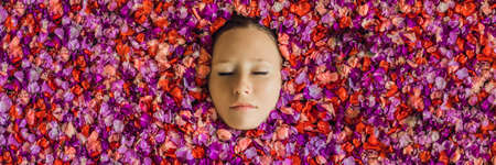 Attractive Young woman in bath with petals of tropical flowers and aroma oils.の写真素材